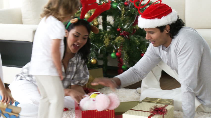 Family opening Christmas presents in the living-room at home. Footage in high definition
