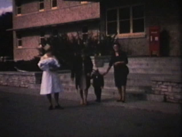 A nurse carries a newborn girl for an excited young mother as she leaves the hospital with her young son and the proud grandmother. (Vintage 8mm film)
