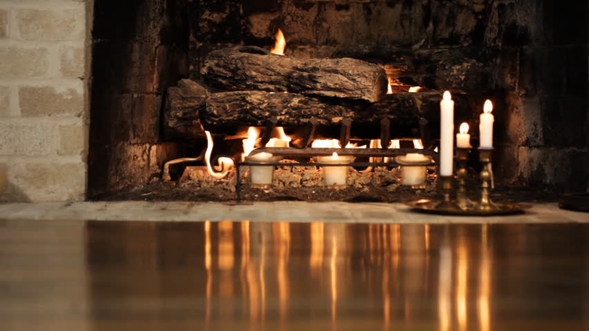Reflections from a blazing fireplace and some candles, flicker on a hardwood floor.