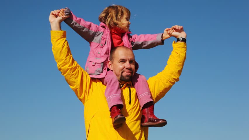 portrait of daughter sits at daddy on shoulders against clear sky 