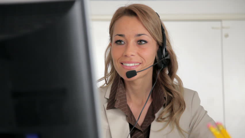 Female receptionist working on computer and talking on the telephone in call center. Sequence