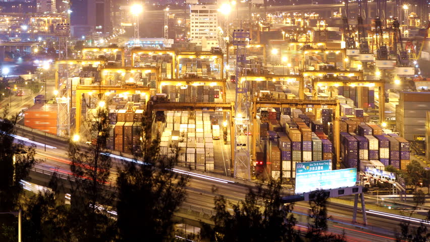 Cargo Container Loading Activity. Timelapse at night. Wide shot. Slowly zooming in. Busy traffice on highway at the front.   