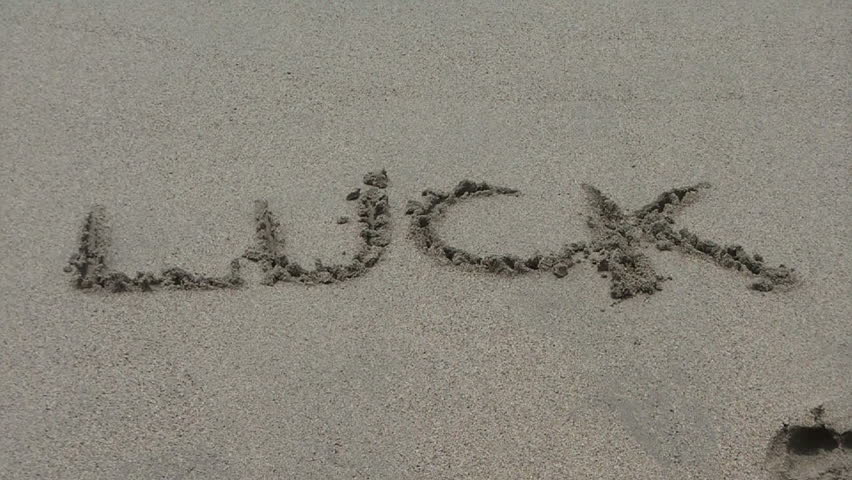 The water wipes off the word "luck" written in sand