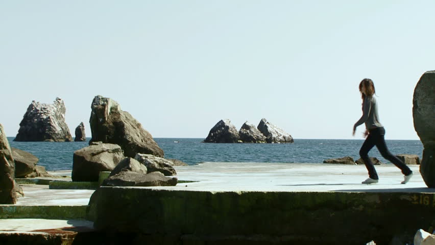 Girl happily dancing. Funny woman dancing energetically around the coastline. 