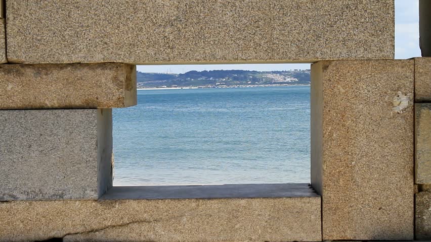 Roller-Skater passing by the beach, framed in a very small stone window