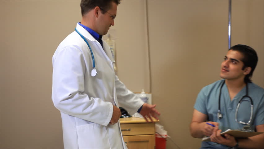 A doctor joins a technician to discuss with his patient the CT scan procedure she is about to undergo.
