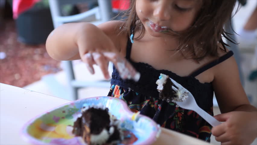 a cute little girl eating birthday cake