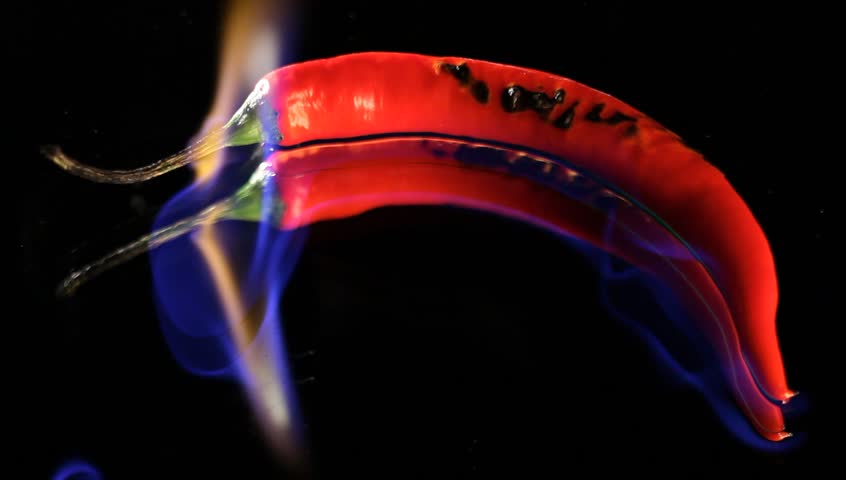 Burning hot Chilli pepper with flame on black mirror background