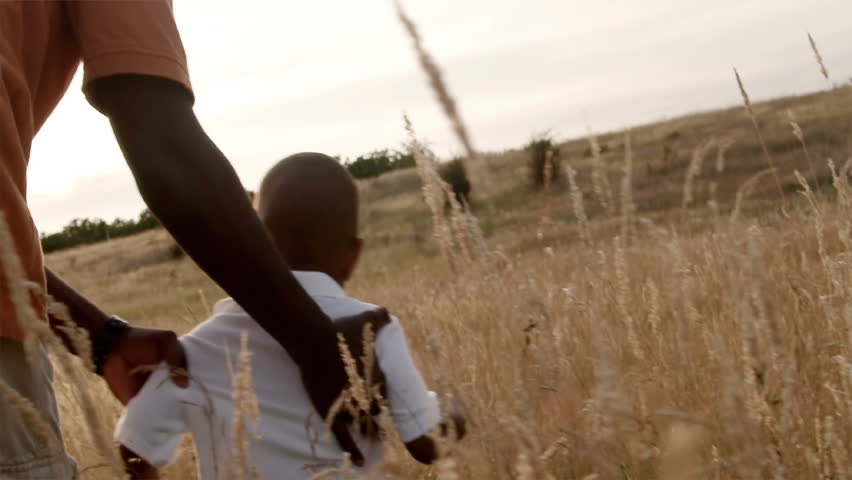 A father and son play in a wheat field on a sunny day.