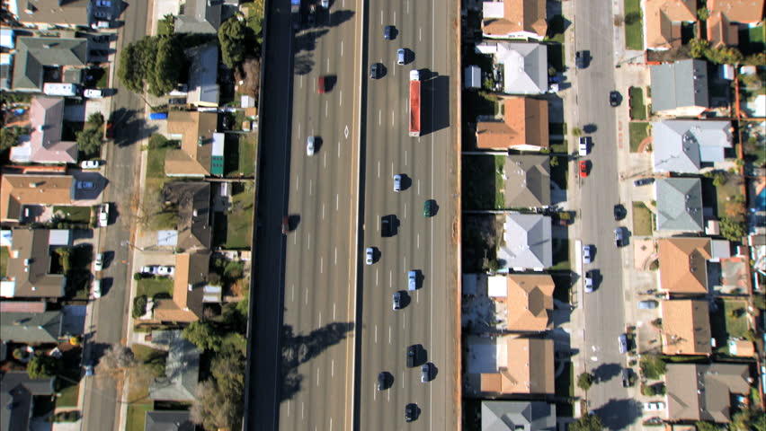 Aerial view following traffic on a freeway with suburban housing either side