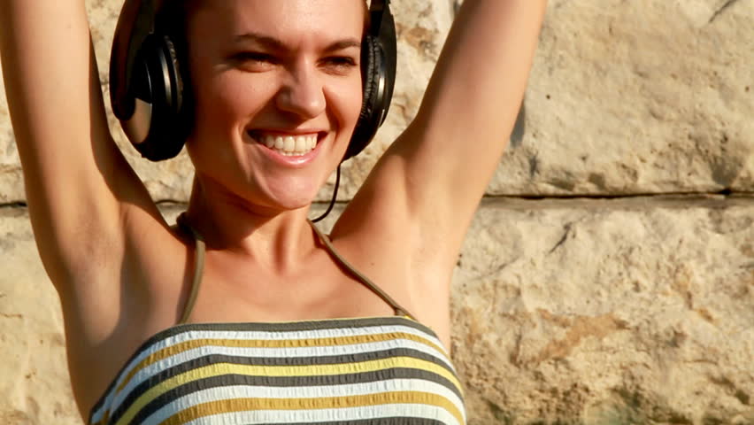Attractive woman with headphones dancing and listening to music, slow motion