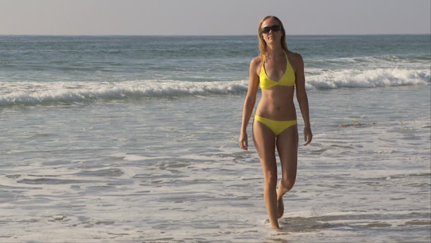 Young woman in yellow polka dot bikini at beach  