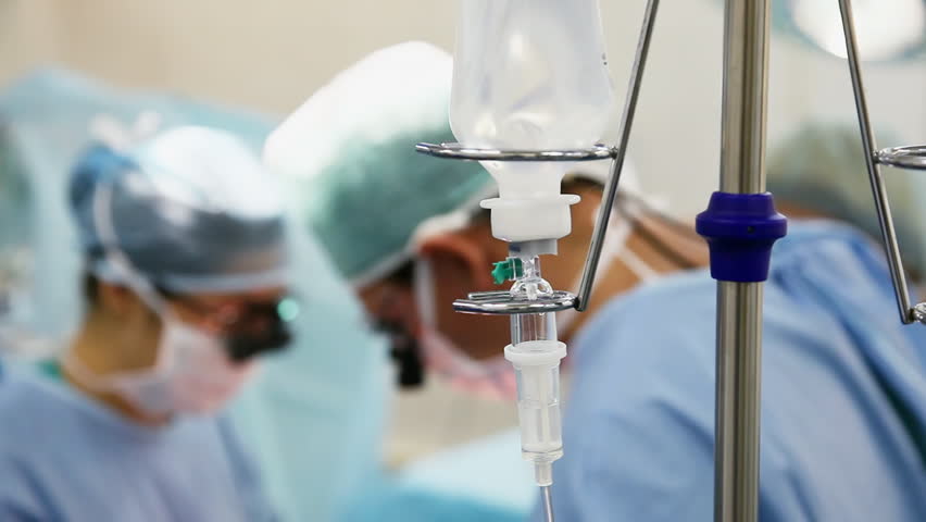 intravenous drip in operation room with surgeons on background
