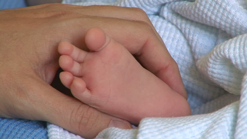 Mother holding newborn baby feet and toes