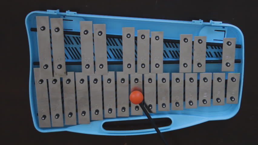 Glockenspiel. POV. Playing a blue children'?s glockenspiel with an orange rubber mallet. 