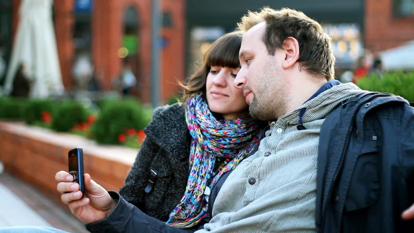 Happy couple in the city taking photo with cellphone 