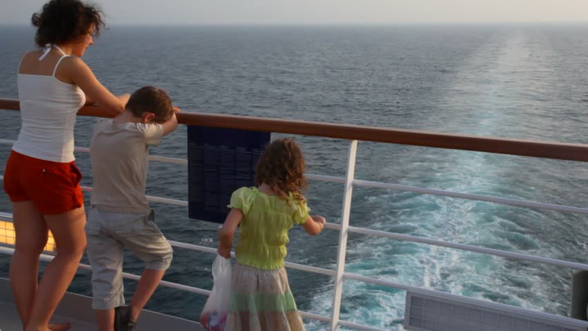 young mother with son and little daughter stand on deck of cruise ship