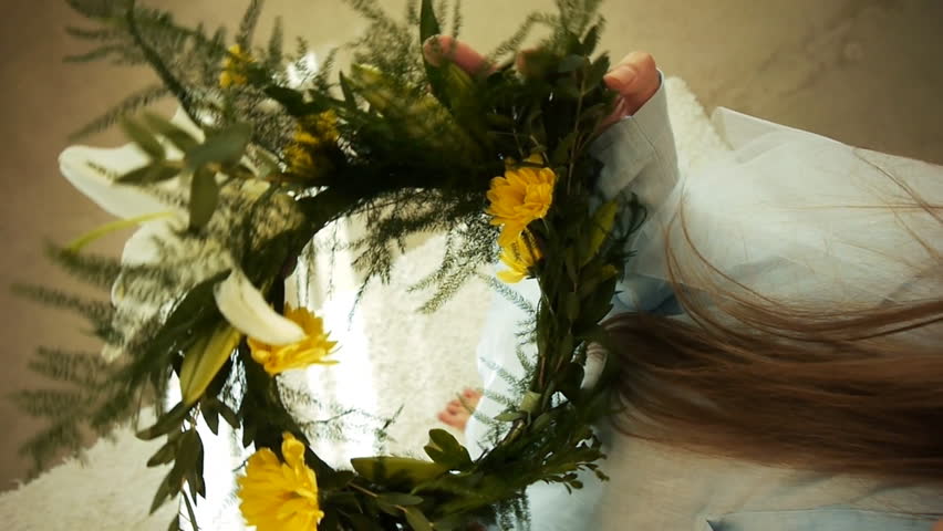 Girl dances with a wreath on her head. 