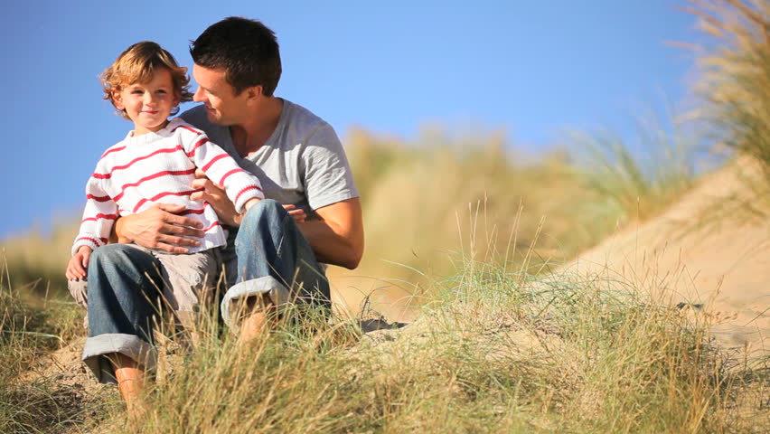 Young caucasian father with his young son happy spending time together in sand dunes by the coast