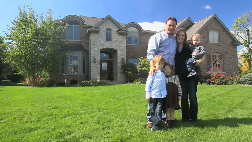 A happy family stands in front of their beautiful brick house 
