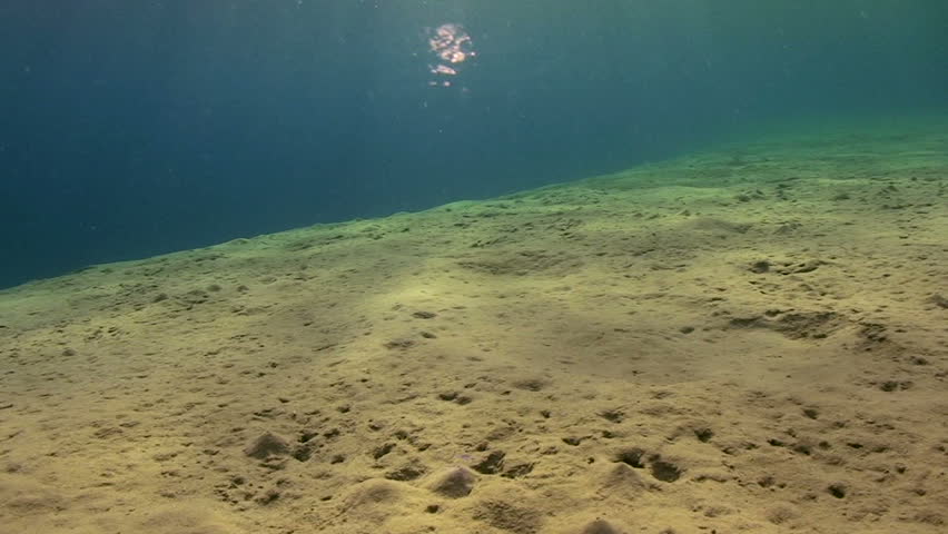 Sandy ocean floor with reflections moving to ocean surface and sunrays