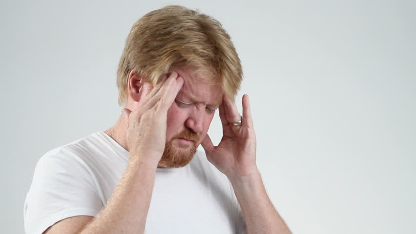 Man with a migraine headache rubs his temple to help relieve the severe pain.
