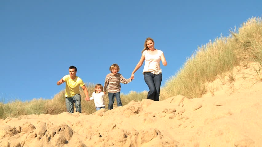 Attractive young caucasian family enjoying leisure time together on coastal sand dunes  filmed at 60FPS