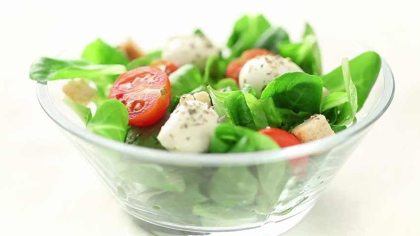 pouring olive oil on freshly made salad