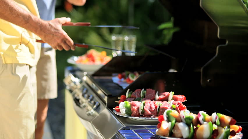 Senior couple cooking healthy grilled food on barbecue