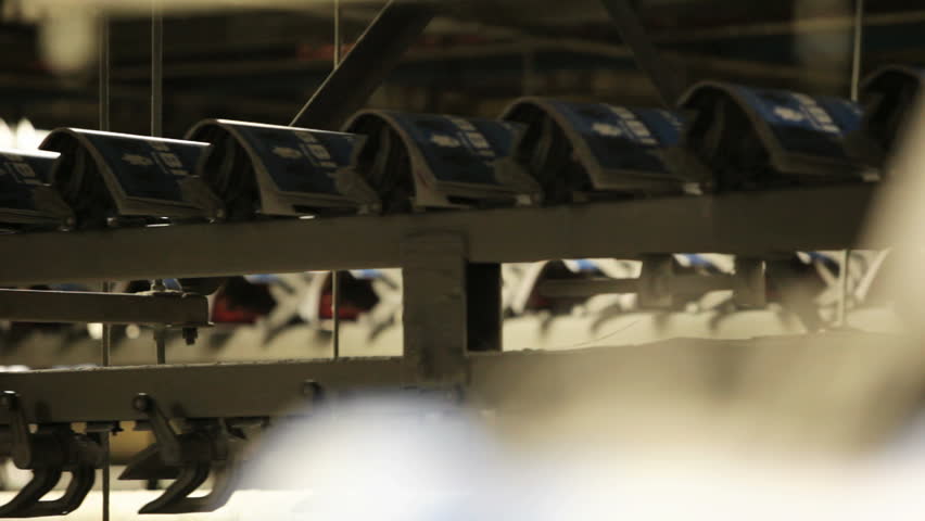Magazines fly past the camera as they make their way along a massive printing press.