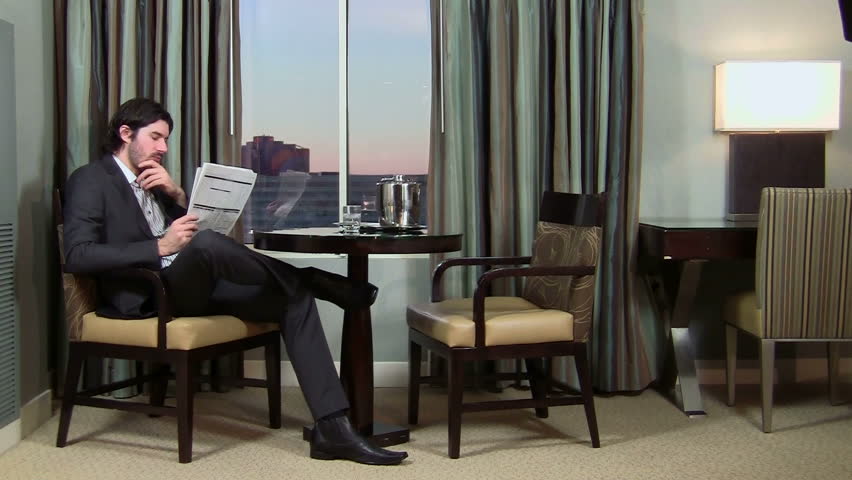 Successful businessman relaxes reads paper in hotel room - HD