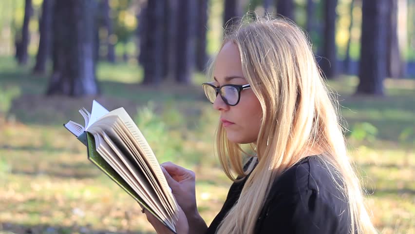 beautiful girl with glasses reading a book