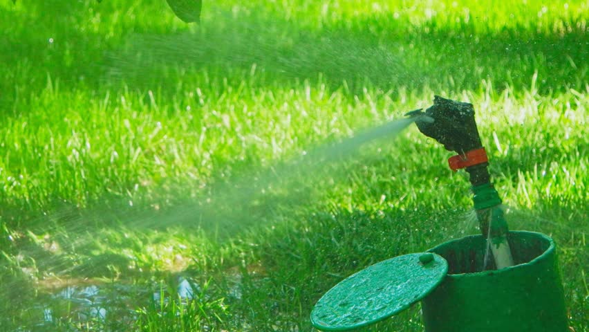 Garden Sprinkler System Working In Backyard Spreading Water Over