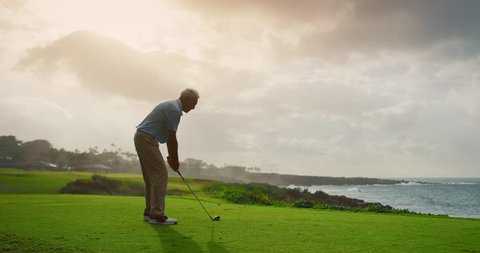 Handsome Older Golfer Swinging And Hitting Golf Ball On Beautiful Course At Sunset By The Ocean Slow Motion