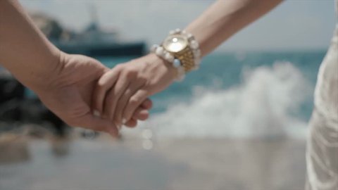 Beautiful Couple Walking On The Beach. Lovers Hold Hands. Santorini Island, Greece. Close-up.