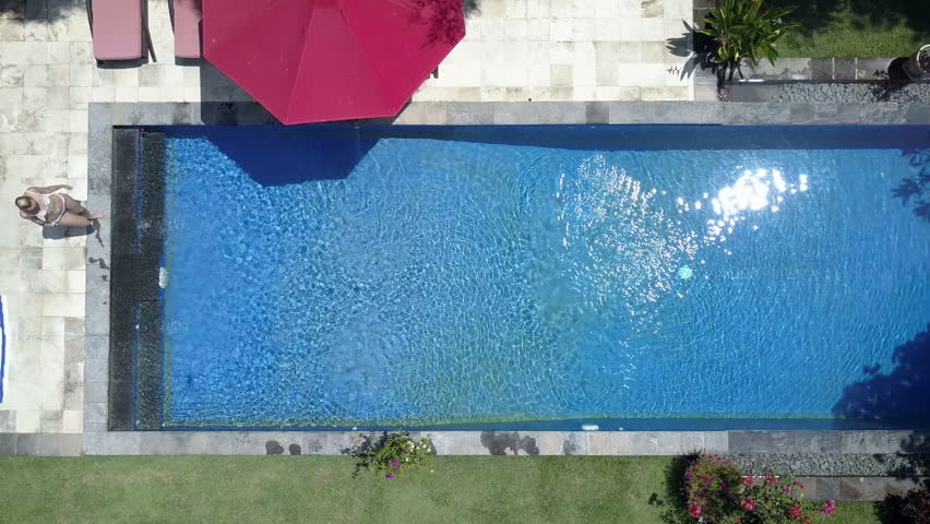 the young beautiful woman swims in the pool in a tropical gardenaerial view from - Rectangle Pool Aerial View the young beautiful woman swims in the pool in a tropical gardenaerial view from - Rectangle Pool Aerial View
