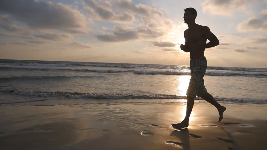 Stock Video Clip of Athletic guy jogging along ocean shore during ...