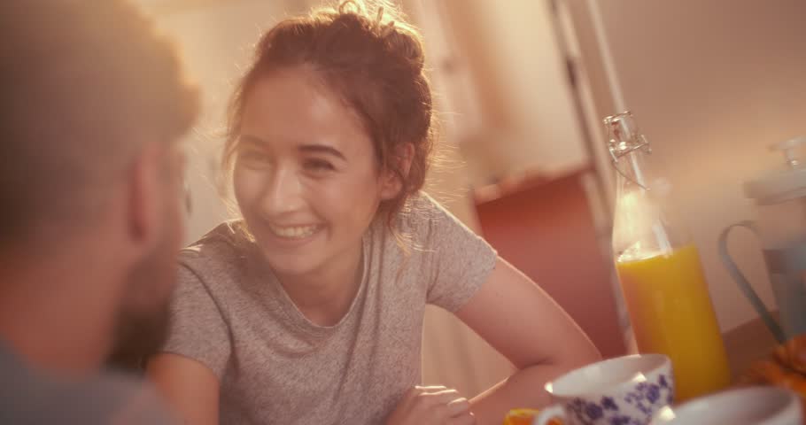 Affectionate young hipster couple being playful while having breakfast together in their apartment kitchen