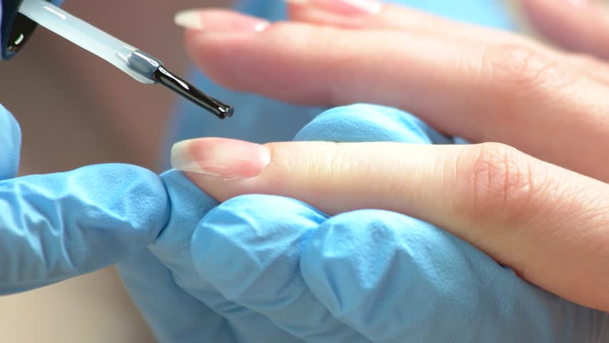 Nail Technician Lying Colorless Varnish Beautician In Manicurist Painting Nails With Varnish Manicure Master In Protective Gloves Lying Colorless Polish On Young