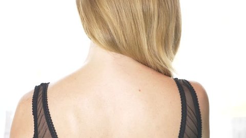 back view, close-up, 4k, slow-motion. a blonde woman takes off a bra strap with one shoulder.