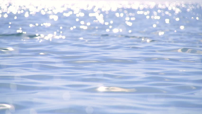 Sparkling fresh wavy water is shining on a sunny summer day in slow motion,