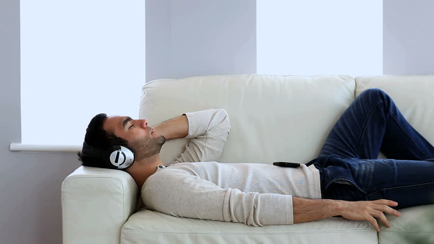 Man Listening To Music With His Smartphone Laid On A Couch